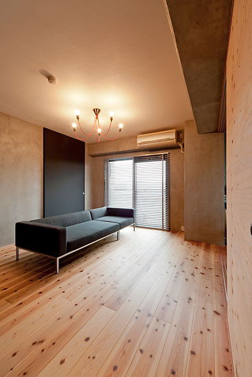 スギの無垢材の床にモルタル仕上げの壁、黒板塗装仕上げの建具が個性的なリビング