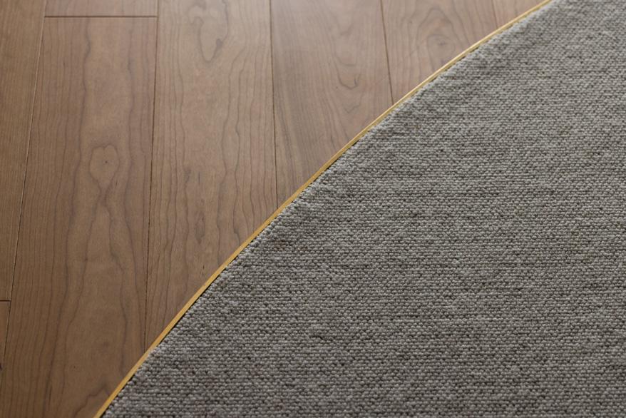 「まるく つつまれて」のアールで区切ったフローリングとカーペット