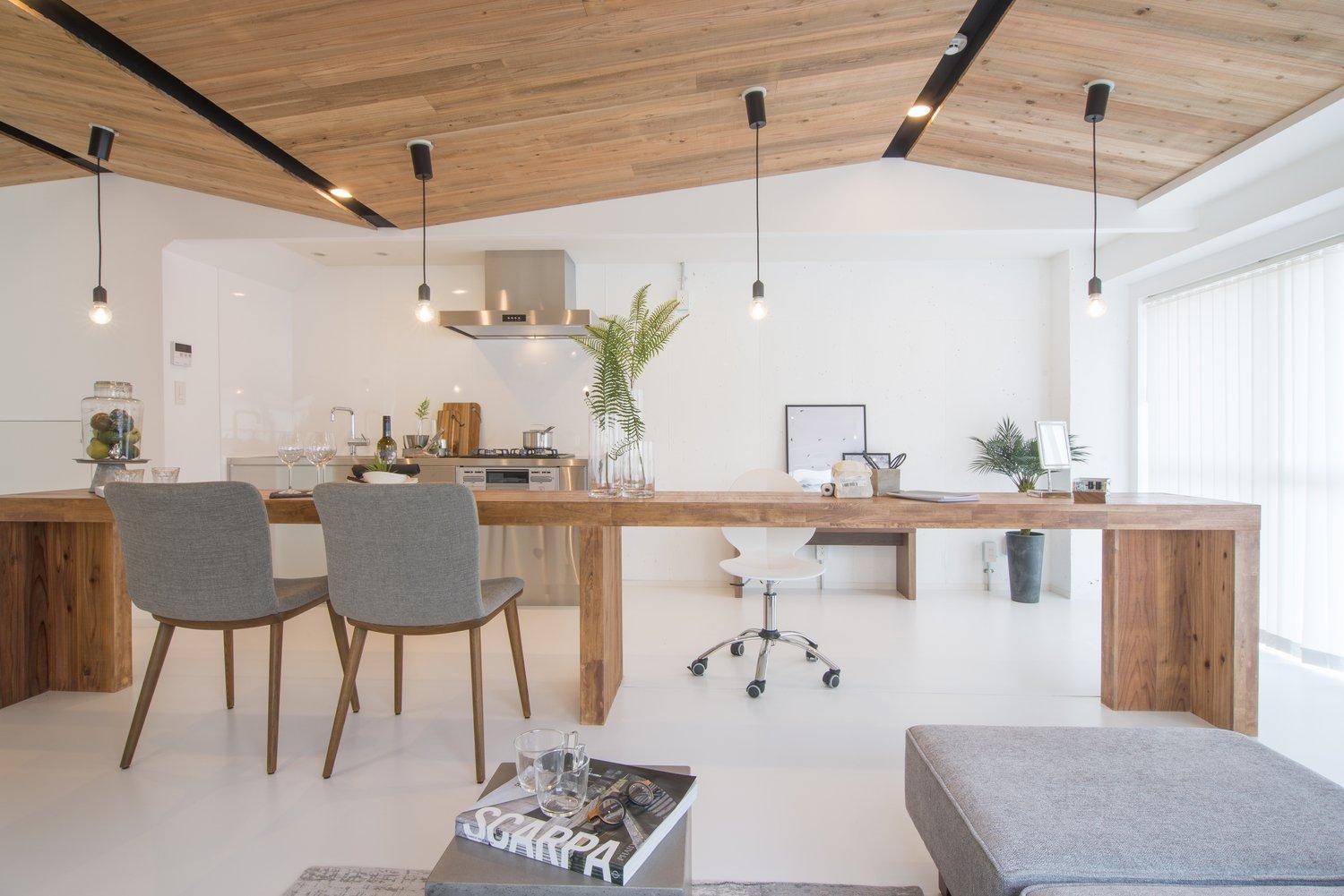 リビングダイニングの天井は無垢板が張られています。
中央にある長い木製のカウンターテーブルと同じ種類の木で、お部屋に統一感が出るようにしました。斜めになった天井は、マンションにありがちな梁を柔らかく隠し、空間に木のやわらかな表情をもたらしてくれています。