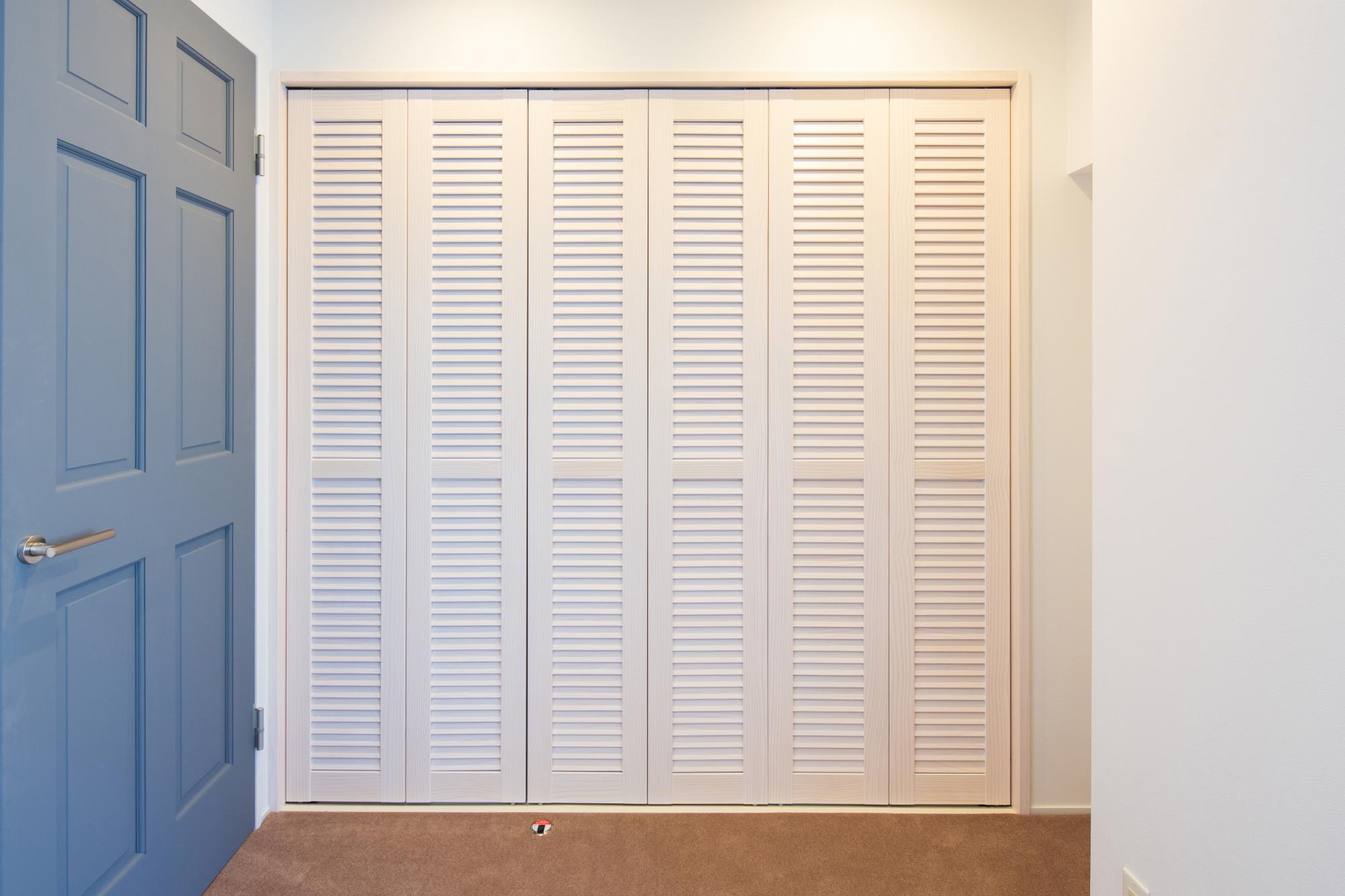 白い収納の扉にはルーバーを設け、リゾート感を出すとともに、空気の換気をする機能も担います。