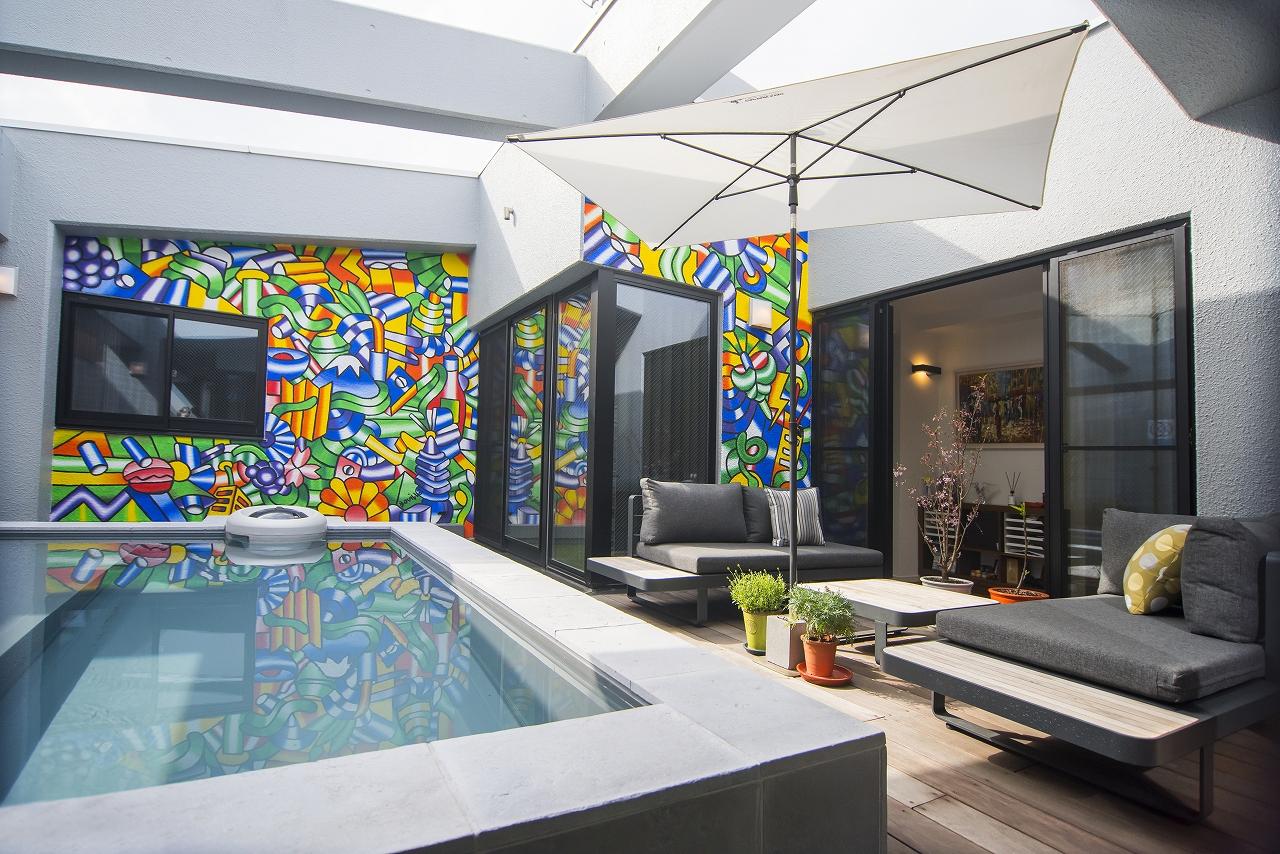 お部屋の中で最も目を引く、プールとその向こうの壁に描かれている色鮮やかなアートです。
たまたま店頭で見つけたアート作品の作者に壁に描くを依頼し、快く引き受けてくださったとのことです。
テラスには以前は池がありましたが、プールに作り替えられました。海外の一流リゾートのような雰囲気を醸し出しています。