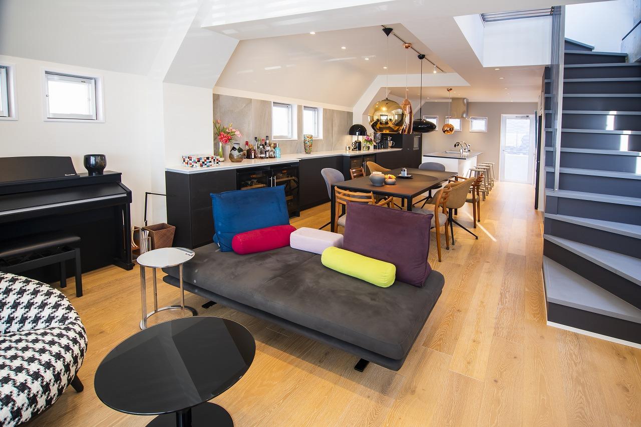 3階の壁は、統一感が出るように色と素材にこだわりました。ソファを置いているリビング側はダークグレー、キッチン側はブルーの壁紙です。ソファがあるリビング側の壁紙をダークグレーにした理由は、窓の枠が一番上まであるかのような錯視を生み出すためです。夜になると、窓枠が天井まであるような雰囲気になります。