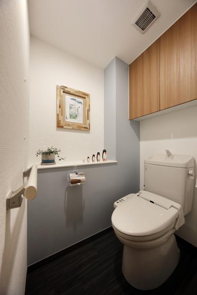 使えるものを大切に活かし、既存の便器は収納も併せてそのままの設備を引き継ぎました。最低限で最も効果的なリフォームを図っています。リビングと同カラーのブルーグレー色を壁の一面に施工してリフレッシュ！コストダウンにも繋がっています。