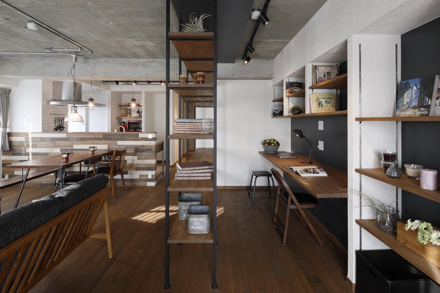 LDKとワークスペースを緩やかに区切ったオープンシェルフ。ご夫婦が並んで作業できるワークスペースです。壁全面が本棚。壁面は黒板塗装です。LDK間をアイアン柱のオープンシェルフがゆるく区切ります。両収納ともに、棚は可動式で取外し可能。生活スタイルに合わせ、柔軟に使える棚仕様です。