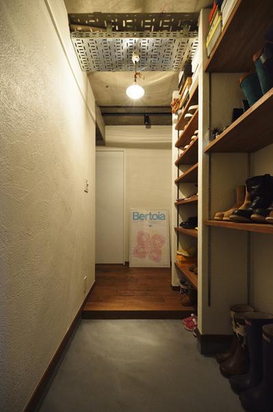 玄関には天井まで届く収納棚を造作しました。扉を付けないオープン式で、靴を「見せる」ディスプレイです。扉が無いことで出し入れスムーズ。目当ての靴がすぐに取り出せます。土間はモルタル仕上げ。照明用に天井に設置した金属パネルがインダストリアル的。