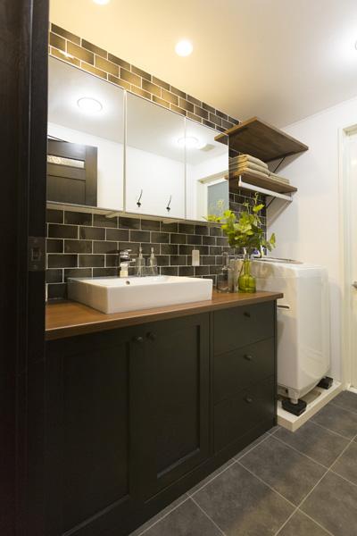 LDKと同じテイストのマニッシュな洗面室です。家族一緒で使える大きめサイズの洗面台をオリジナル造作しました。オープン棚で収納も強化。ハンガーパイプは“ちび物干”として大活躍中。