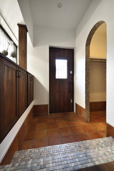濃い色彩でも重すぎない品格ある玄関です。建具は家具はオリジナルで造作しました。リズミカルなタイルはペールカラーの組み合わせで優しさを演出。アーチの先は二世帯に見合う大容量のシューズインクロゼット。コート置き場も兼ねるなど生活がもっと便利に。