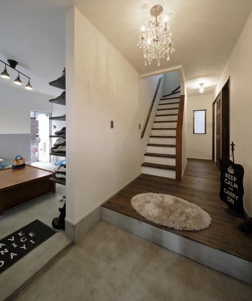 シャンデリアとモルタル土間の意外なカップリングがお洒落な玄関です。床は深いトーンの無垢パイン材。土足のまま大きな土間につながります。土間の奥からはユーティリティへ入室OK。