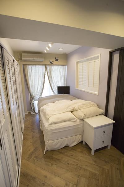 寝室には、両開きのルーバー窓を新設しました。窓からは1階を望むことができます。プライバシーを確保しながら採風も可能になりました。 淡いラベンダー色の壁がやわらかな印象に。ウォークインクローゼットをなくし、壁一面 クローゼット収納としました。ヘリンボーンに見える床はフロアタイルです。