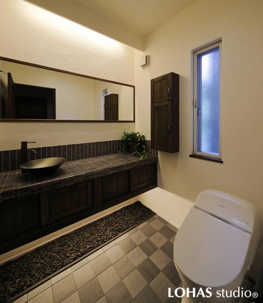 ホテルのように重厚な和テイストのトイレです。浮かせた足元には玉砂利を敷いて野趣あふれる空間を演出。床はメンテナンス性のよいフロアタイルを選びました。