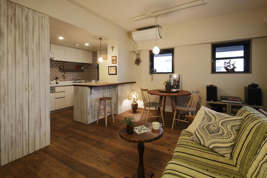 珪藻土を施したミルク色の室内。素材が土のため、クロスと全く異なる質感です。キッチン手前の天井までの収納の扉は、カウンターの羽目板と揃えたヴィンテージ調。 カリフォルニアンテイストの爽やかな室内に、空色の室内扉にイエローの照明がおしゃれに彩りました。床は手を加えるほど味の出る無垢フローリングです。