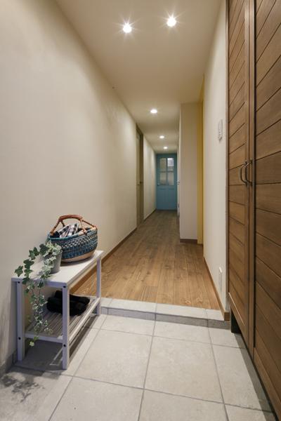 シンプルな造りの玄関には天井まで届く、大きな玄関収納を設けました。 たたきの上がりは、土間と同じタイルをあしらい、個性を感じさせます。 廊下に入ると個性的なドアが並んだ楽しいアプローチ。ブルーのドアはリビングに通じています。色鮮やかなドアは、1部屋ずつ違ったノブを選んでいます。