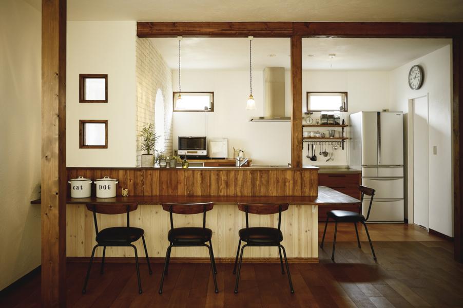 キッチンと向き合う ダイニング兼カウンターです。側板を塗り分け インテリアの存在感を惹き立てました。 飴色の梁はキッチンを囲む美しいフレームに。ゆったり過ごせる和み空間です。