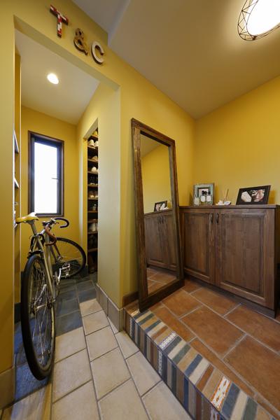 イエローを配色した軽やかな玄関です。色数多めのタイルバリエーションでも色の合わせ方でセンス良くまとまる好例。タイルを斜め張りしてリズム感も加えました。土間奥は大型のシューズインクローゼット。定番の靴や傘のほかアウトドアギアの置き場に活躍中！