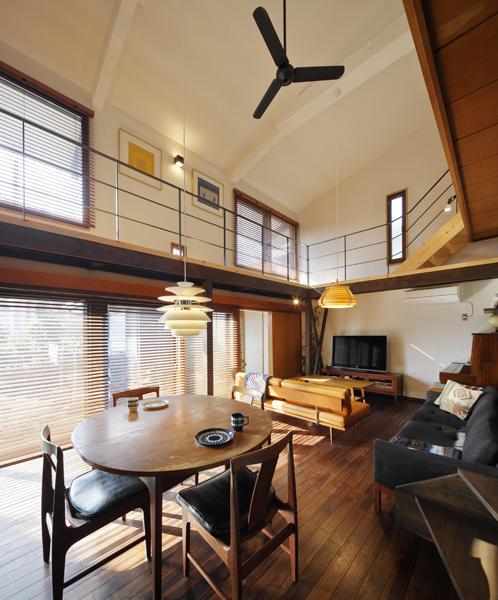 吹抜けを仰ぐ開放的なLDKです。庭に面した縦横の窓から日差しが惜しみなく届きます。室内を彩るストライプの影模様も周到なデザインのひとつ。豊潤な床面はウォルナット仕上げ。全体を重厚なトーンで包み 飽きのこない風景を創りました。