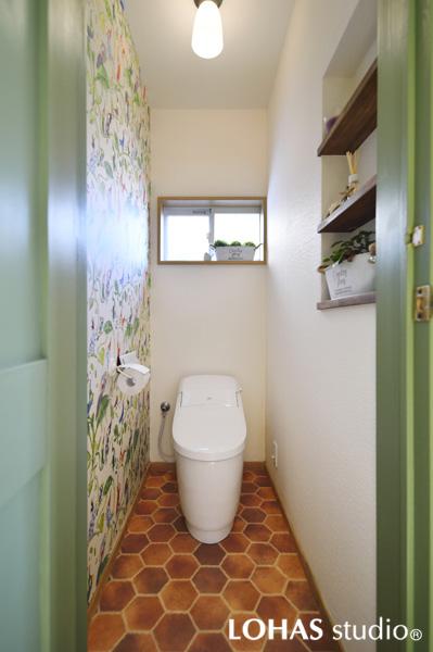 ボタニカルな装いに刷新したトイレです。床にはハチの巣箱 壁には鳥たちが歌うグリーンのクロスを装いテーマ性のあるインテリアデザイン。賑やかで美しい室内に 控えめなグリーン色の扉が好相性です。既存の収納を撤去した跡には雑貨や小物が飾れるオープン棚を造作しました。