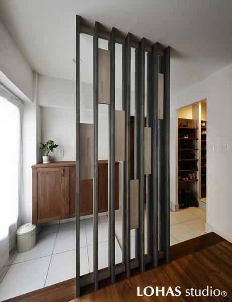 パーティションで上手に視線を隠した玄関です。シックなタイルで大人の装いに。小さな個室をまとめ、ゆとりの空間に仕立てました。オリジナルの玄関収納は足元を浮かし土間を広く見せています。