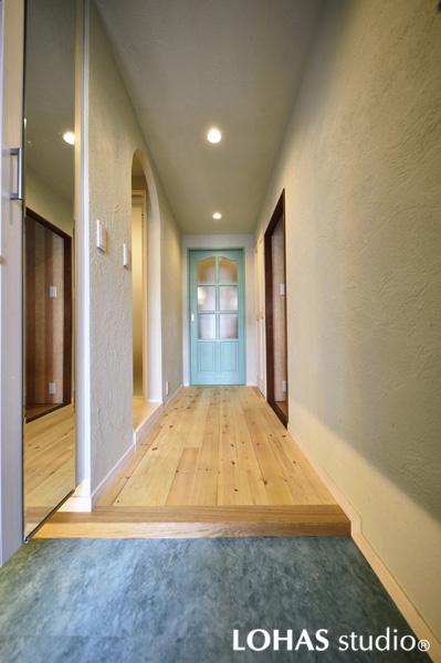 ザックリした塗り跡を壁全体につけた上質な雰囲気の玄関です。明るい無垢パイン材をフローリングに用いて「暗い感じ」を払拭。窓のある扉を造作して奥の部屋からも光を導きます。アーチ型のオープン開口で圧迫感も解消！