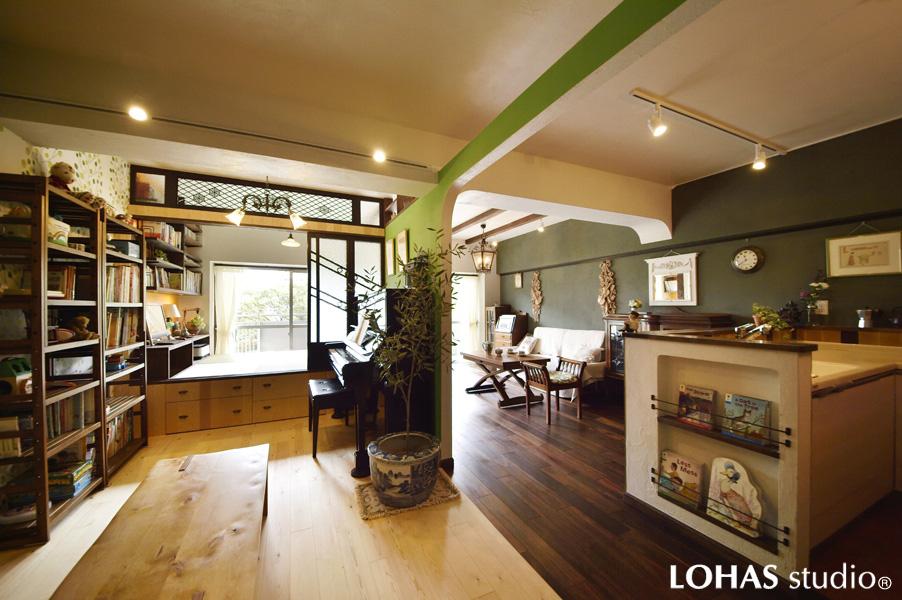 オープン間仕切り越しに隣室を眺めるLDKです。縦2列のレイアウトが個性的。重厚感ある床は無垢ウォールナット材。質感豊かな壁・天井は珪藻土を塗装しています（白・深緑色）。