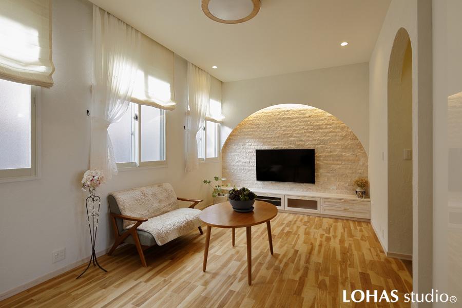弧を描くデザインとカーテンの透け感でフェミニンな装いのリビングです。ヨーロッパの路地風景をデザインしました。淡く澄んだ色合いの床は縮れ杢が特徴の無垢カバザクラです。