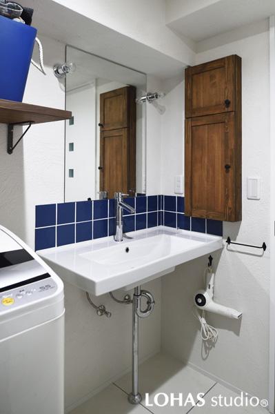 ブルーが挿し色の清涼感ある洗面室です。洗面ボウルを自立させて足元はスッキリ。デッドスペースを使って棚を造作し収納力を増やしました。床はスタイリッシュな大判のタイルです。