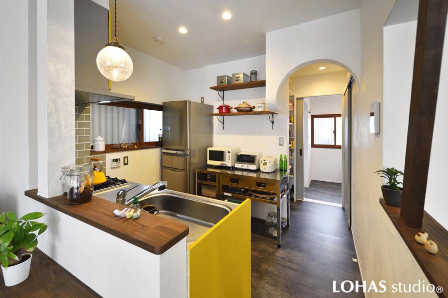小粋なイエローをご採用されたキッチンです。曲線が優しい下がり天井からパントリーへ、さらに奥の廊下へと回遊できる便利な動線を計画しました。床にはメンテナンス性の高いクッションフロアを施工しています。