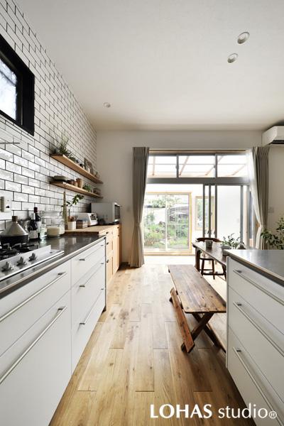 白を基調にした明るいキッチンです。壁全体に施工した艶のあるブリックタイルで清涼なスタイル。造作したオープン棚にグリーンが瑞々しく映えています。