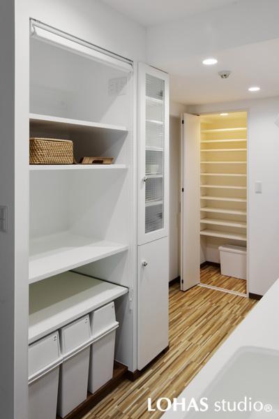 白基調のキッチン収納とパントリーです。収納棚にはロールスクリーンで"目隠し"を設置。扉がないので物の出し入れが容易です。奥のパントリーは小さな個室に可動棚を天井近くまで造作しました。