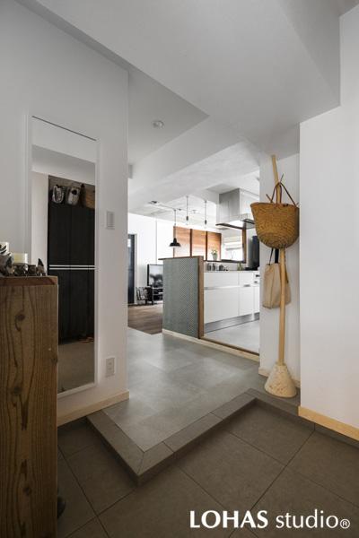 すぐにキッチンと繋がるオープンな玄関です。カギ形の動線でリビングからの視線も気になりません。土間は明るいグレーのタイル素材を採用。通路側は同じトーンに揃えつつ踏み心地の良いフロアタイルを施工しました。