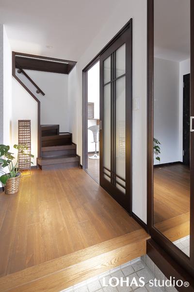 透明感のある建具と鏡の効果で光を感じる玄関です。フローリングはLDKと同じ素材のパイン無垢材を施工しました。新しく張り替えたクロスの白さが木素材に調和して南国の装いに。