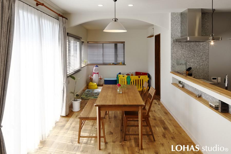 アーチからフリースペースを眺めるダイニングです。天井や壁は淡いグレーのエコクロスをご採用。天然素材の無垢床がナチュラル感をより演出。