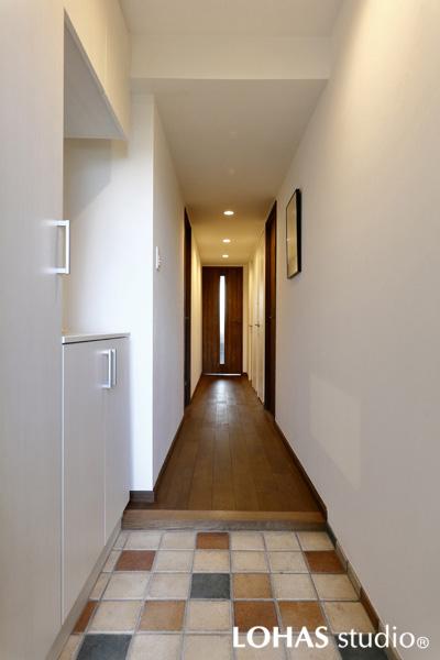 白く囲んだ空間に色とりどりのタイルデザインが新鮮な玄関です。ロッカーや下駄箱などの収納をコンパクトにまとめました。奥の扉から光が差し込み閉塞感を感じません。