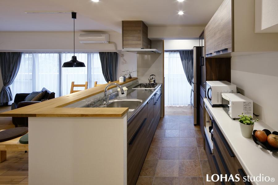 家事のしやすい回遊動線の対面キッチンです。スレート石材の表情を持つタイルを床に施工。レンジフードに木調パネルをあしらうなど上質な世界観にこだわりました。