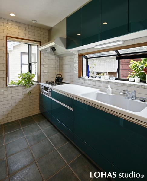 グリーン色の愛らしいキッチンです。壁面に光沢の美しいブリックタイル、床にはシックな色彩で焼きムラのあるテラコッタ調タイルを施工。表情のある素材選びで上品な雰囲気に完成。