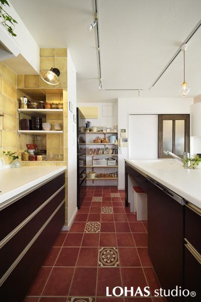 朗らかなタイルデザインに心華やぐキッチンです。システムキッチンは白と茶のメリハリある組み合わせでシックな装い。奥には使いやすいパントリーを造作しました。