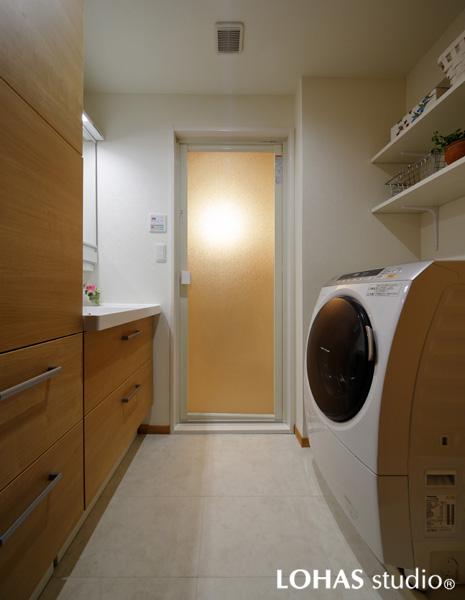 木調の温かさを感じる清潔な洗面室です。焼き物のような表情を持つフロアタイルを床に敷きました。洗濯機の上には便利なオープン棚を造作。