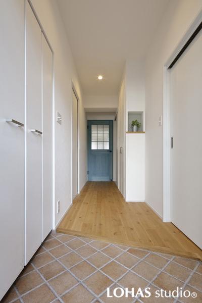 格子窓の建具やニッチが印象的な玄関です。建具の色を白に揃える・リビング扉に窓を造る工夫で明るい空間に変わりました。室内壁・廊下に大きな収納を新設しています。