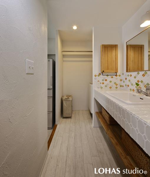 元気なビタミンカラーが爽やかな洗面室です。白い木調の床は水濡れに強いクッションフロアです。室内干しハンガーを設置するほか脱衣室側に棚を造作しています。