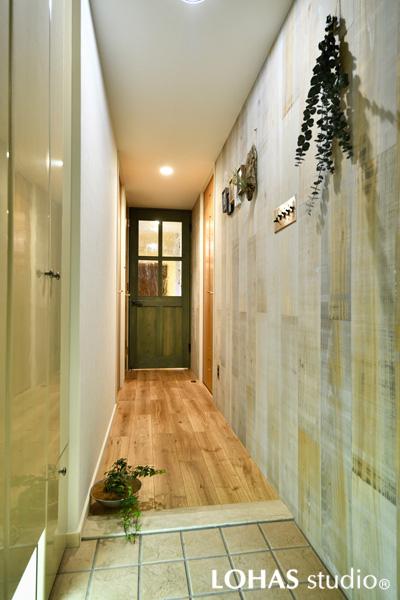 壁に古材風の羽目板を施工した玄関です。木の材質には国産杉やタモ材を使用。ラスティックな風合いに乱張りで遊び心を加えました。