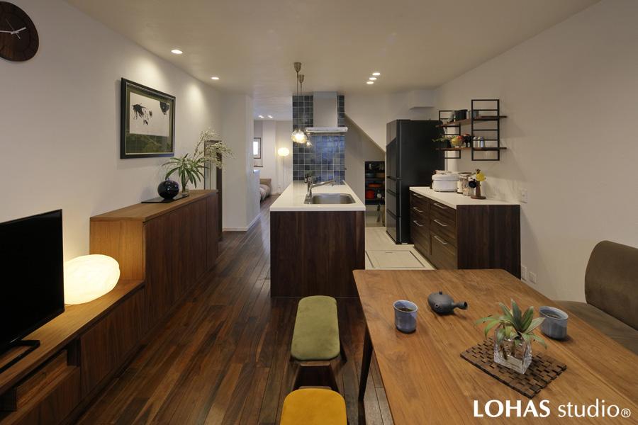 ミッドセンチュリーなインテリアの似合う1階フロアです。照明光がふんわりと光る壁や天井は白い珪藻土の塗装。存在感のある「KOMA」家具と床の素材を無垢ウォルナット材で揃えました。