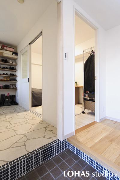 2WAYの動線を持つ使いやすい玄関です。玄関土間には雰囲気のある割肌石のフロアタイルを施工しました。框に施工したブルーのタイルが空間を引締めています。