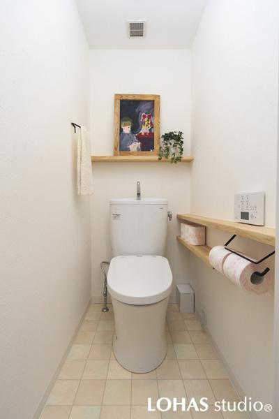 シンプルで優しいイメージのトイレです。自然の色合いが心地良い無垢アッシュ材でカウンターや飾り棚を造作しました。壁・天井は環境に優しいエコクロスです。