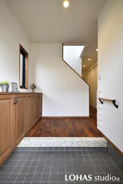 広々としたシンプルな玄関です。框のモザイクタイルや壁のブリックタイルでレトロな雰囲気を造りました。窓枠も色を調えてデザインを統一。