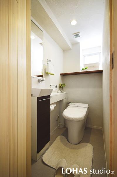 珪藻土のパターンが印象的な清潔感のあるトイレです。タンクレストイレを選んで室内はすっきり。自然な色変化や濃淡差の楽しめるフロアタイルを床に施工しました。