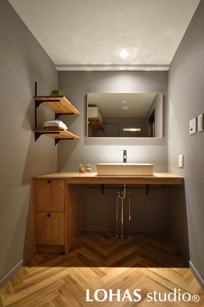 木目のナチュラルな色合いが安心感を与えてくれる洗面室です。洗面台は新たに造作し、床はヘリンボーン柄のフロアタイルを施工して、シンプルでありながら上品な空間にまとまりました。