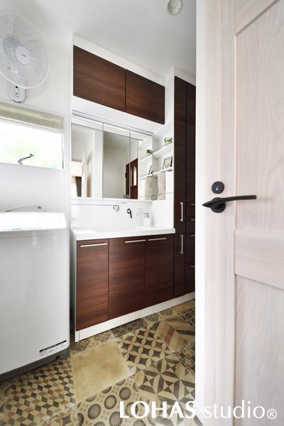 「なにより服が脱ぎやすくなったのが一番うれしい」とお喜びの声をいただいた洗面室です。廊下側とリビング側の2方面から出入りができてより便利になりました。床のフロアタイルはN夫人が非常に気に入られて、工事現場でチェックしながら貼りあわせを考えたこだわりの場所です。