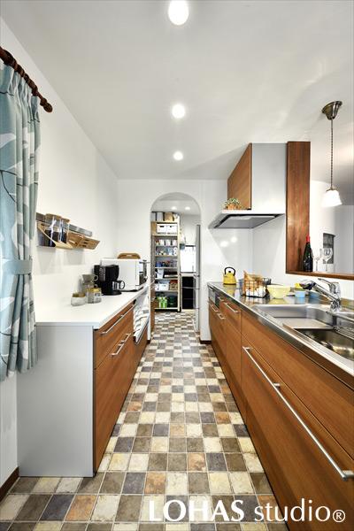 既存の配管・ダクトの位置を念入りに調整し、移動させることが可能となったキッチンです。床はタイル調のクッションフロアで楽しげな様子となりました。アールの下がり壁でさり気なく区切られた奥には大容量のパントリーと、奥様の趣味の部屋が。