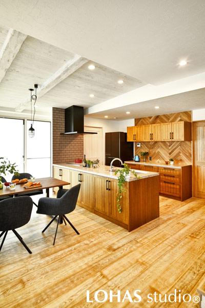 ヘリンボーンが印象的な、ウッディテイストで固められたキッチンです。奥には稼働棚式のパントリーを設けて収納面もばっちり。コンロ横には、不揃いさが味わい深いタイルを施工して汚れ対策にもなりました。