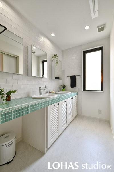 クリーンな印象の、ホワイトとグリーンでまとめられた洗面室です。手洗いボウルと鏡も複数設置して、家族で並んでも渋滞しないつくりです。鏡は収納鏡になっており、雑多になりがちなコスメ類などがすっきりとしまえて便利。