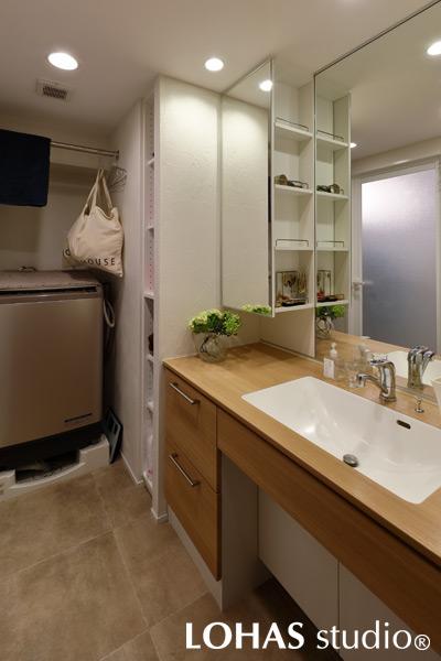 大きな鏡が印象的な洗面室です。今回のリフォームは築浅物件だったため、住設機器のほとんどをそのまま利用しています。洗面台は既存を使用して、天井にエコクロスを、壁には珪藻土を施工。LDKとは塗りパターンを違うものにして変化を付けました。